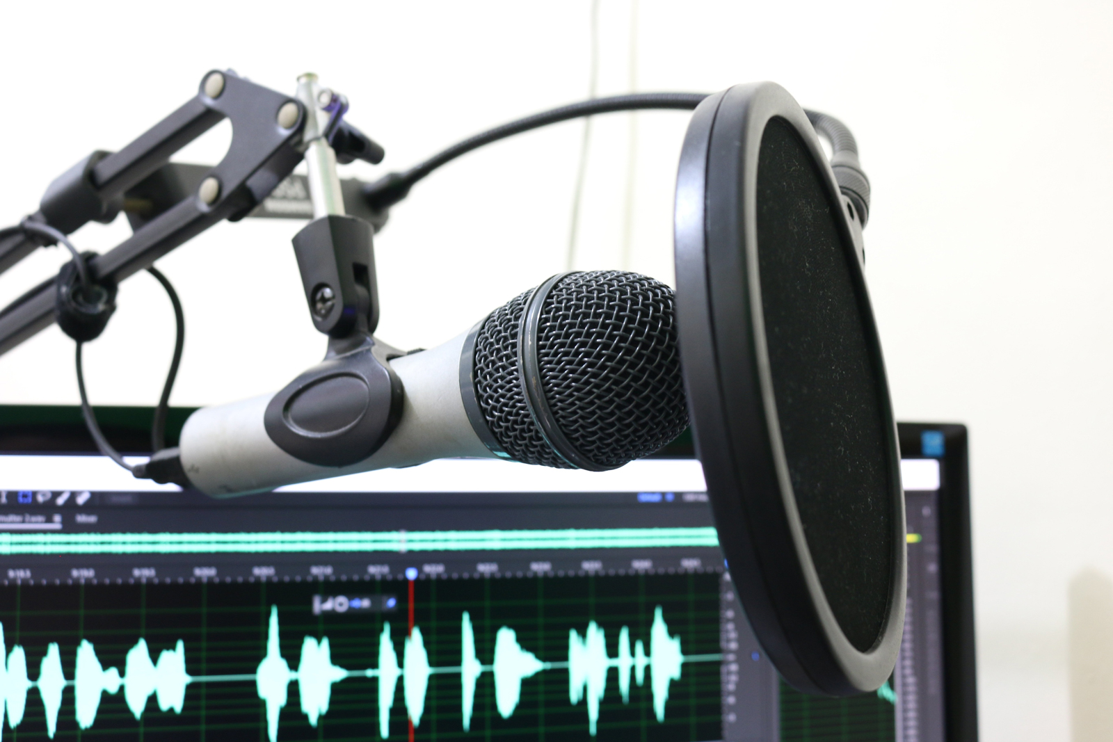 A podcast microphone set up with a screen receiving sound in the background