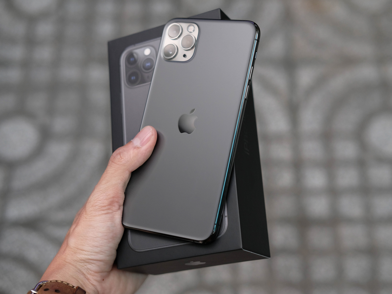 A person holding an iPhone 11 Pro Max ad its box