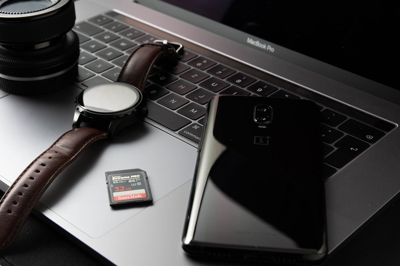 A OnePlus 8 Pro on an open Macbook next to an SD card and a smart watch