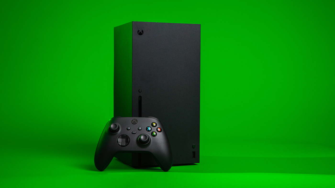 An Xbox Series X with a controller against a green background