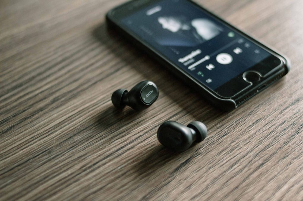 In-ear headphones on a desk next to a mobile phone