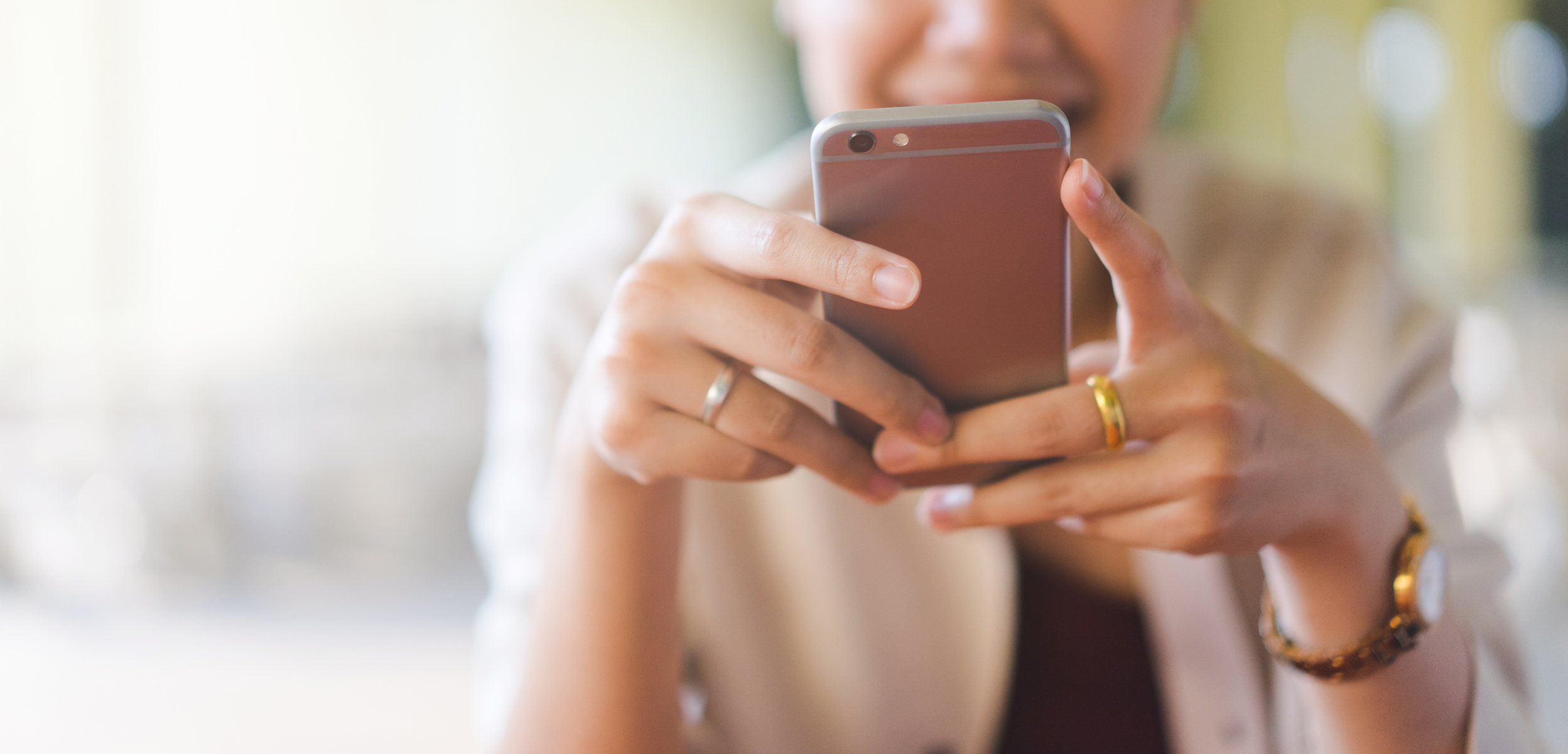 A woman sitting down using her mobile phone while smiling