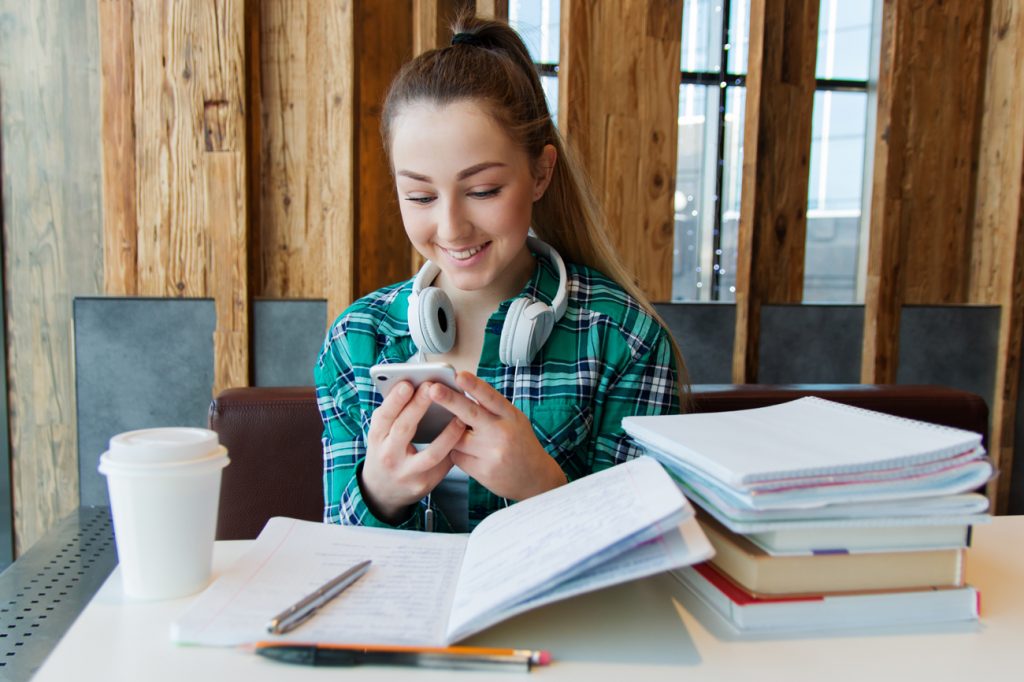 A student sitting at a desk studying and listening to music on headphones