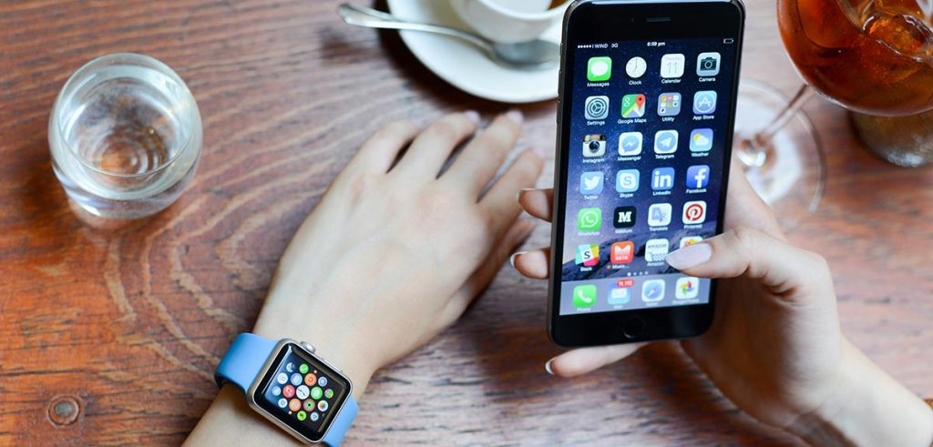 A person sitting at a table with a coffee using their iPhone and iWatch together