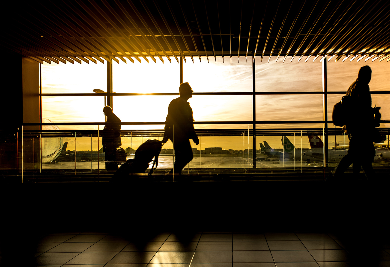 People walking through an airport terminal at sunset