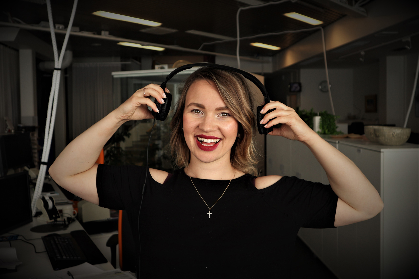 A woman adjusting her headphones listening to a podcast