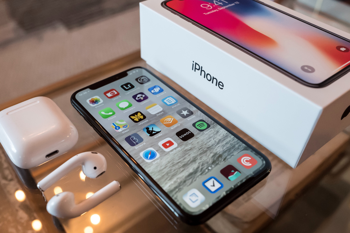 An iPhone placed next to its box and Airpods