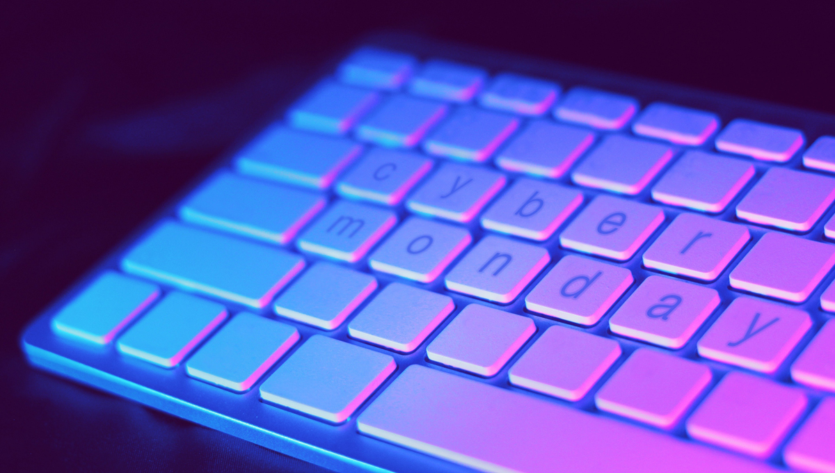 A blank white keyboard with the words Cyber Monday spelt across it under a purple light
