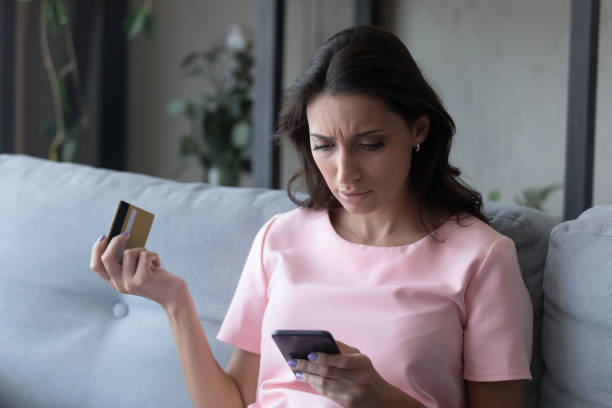 A woman holding a credit card whilst using her mobile phone