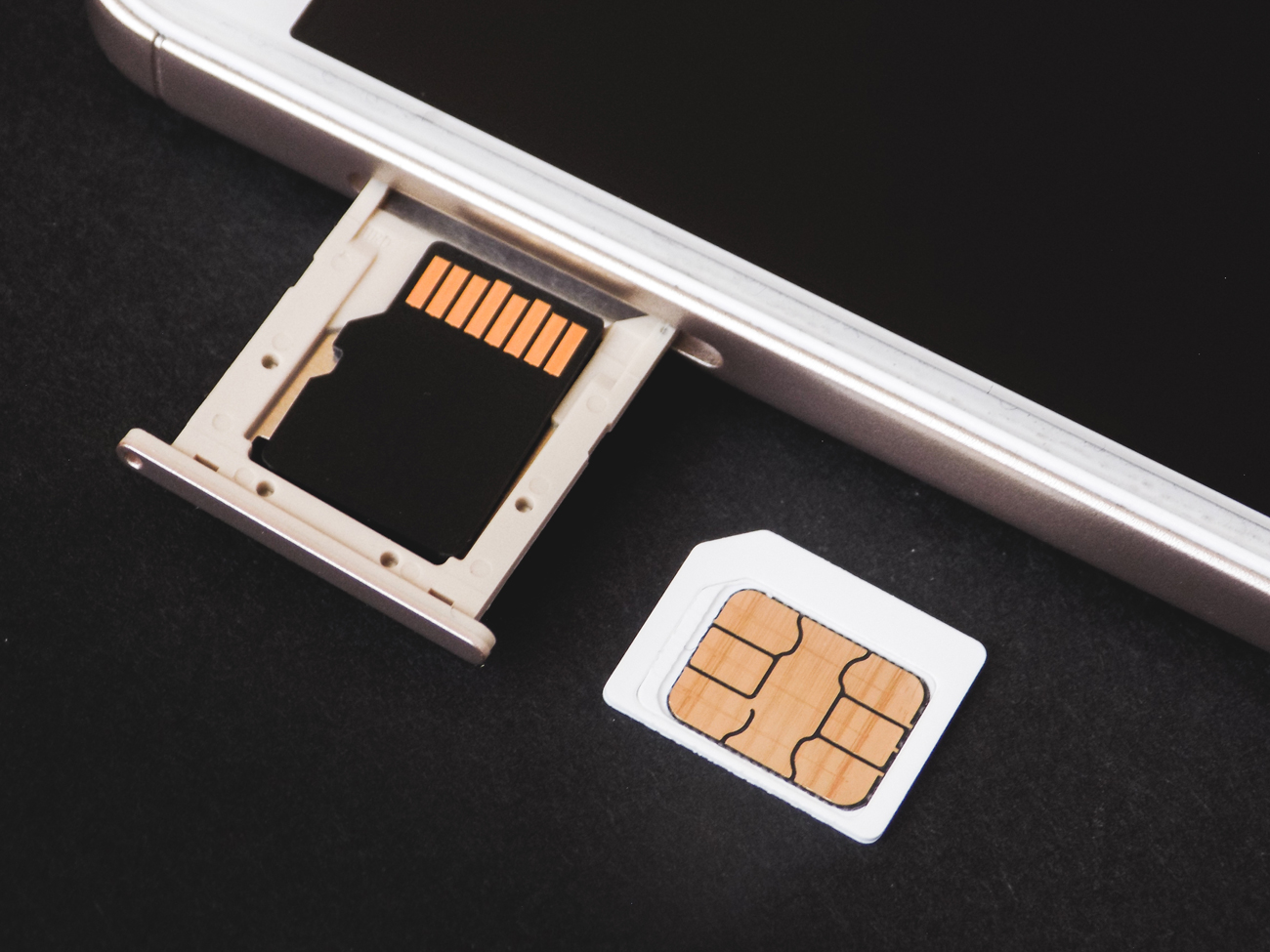 A mobile phone with its sim tray open and a sim card next to it