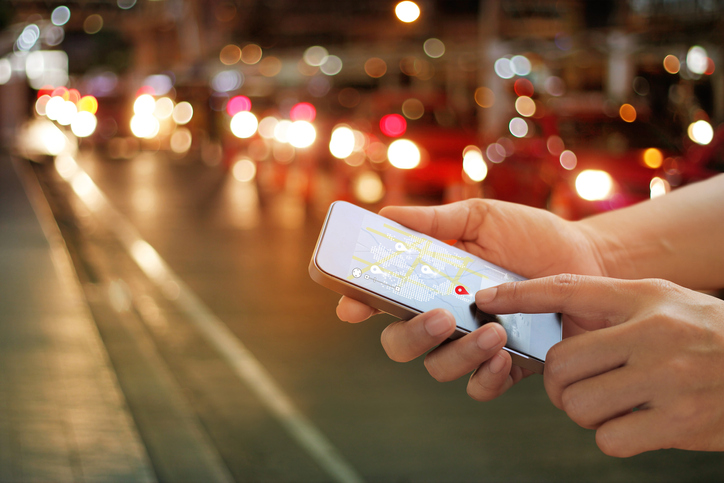 A person using a safety app on their mobile phone on a city street at night