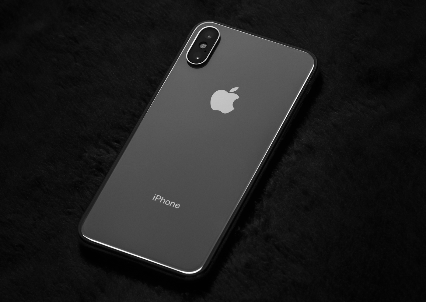 A black iPhone XS face down on a black background