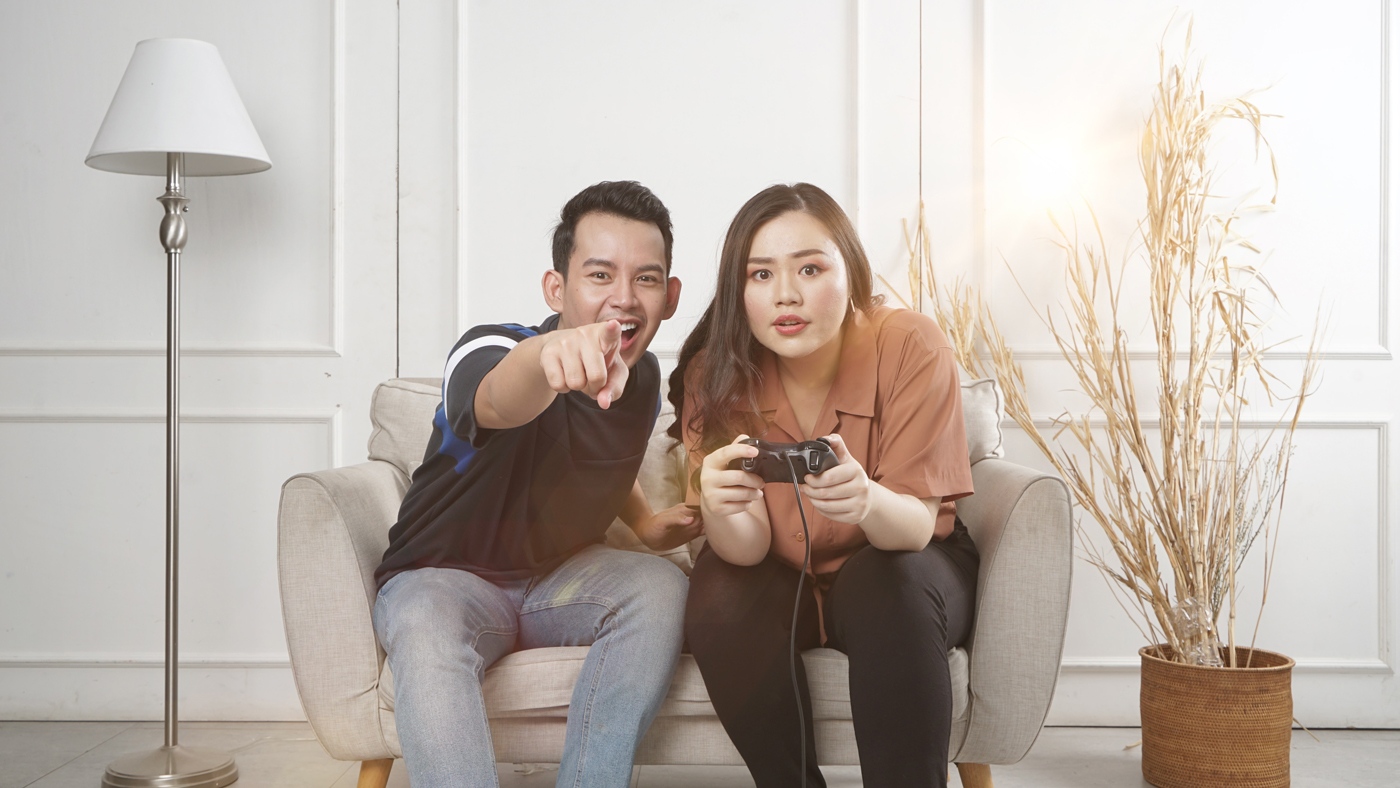 A couple sitting on a living room sofa gaming together