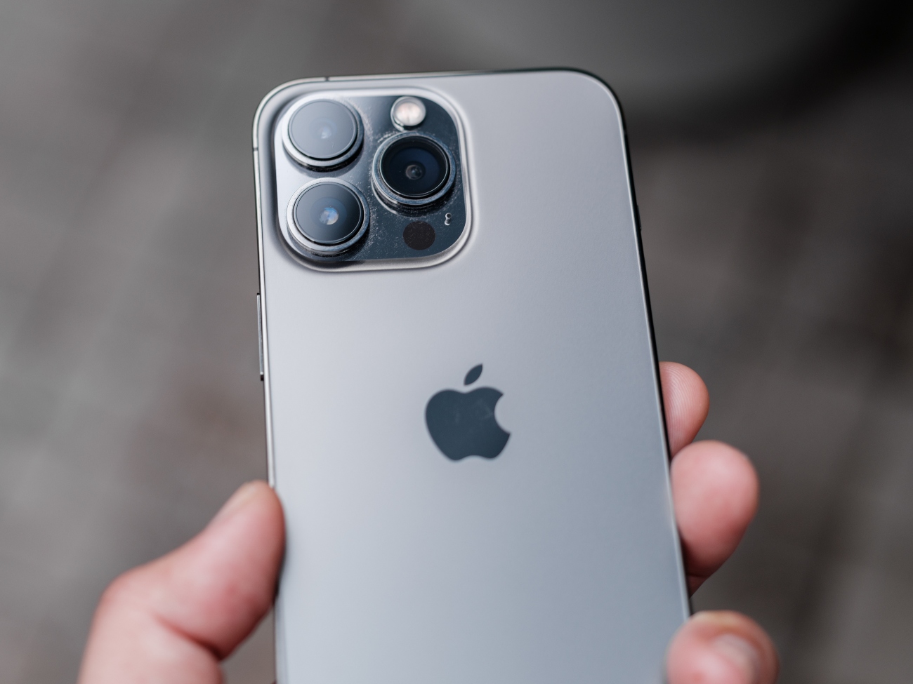 A close up of a space grey iPhone 13 Pro Max in someone's hand