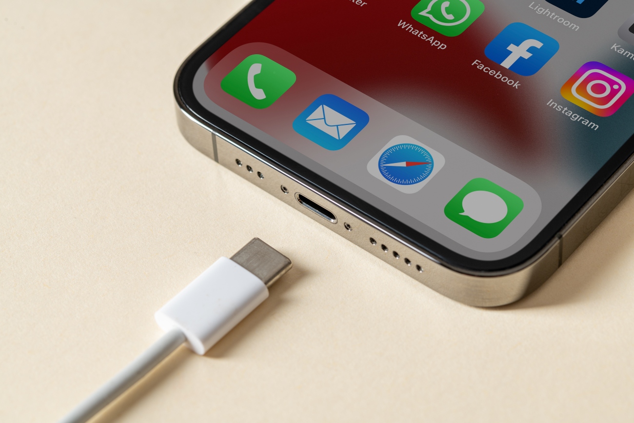 A USB-C charger shown next to an iPhone 13 Pro Max laying flat on a table